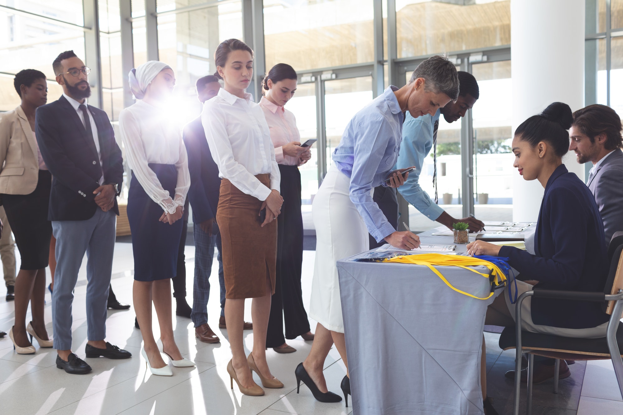 Businesswoman and businessman signing in at conference registration table while group